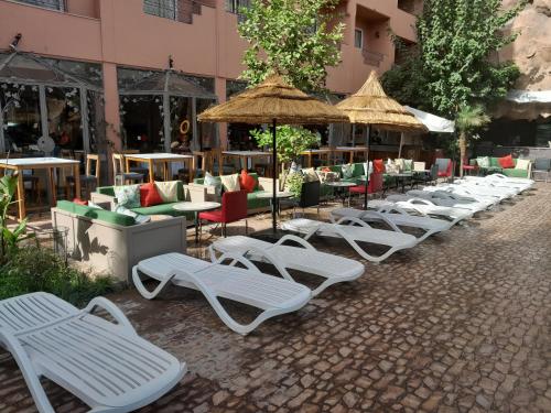 a row of lounge chairs and umbrellas in front of a building at Imperial Holiday Hôtel & spa in Marrakech