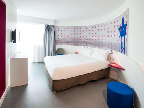 - une chambre avec un lit blanc et un mur rouge dans l'établissement Ibis Styles Collioure Port Vendres, à Port-Vendres