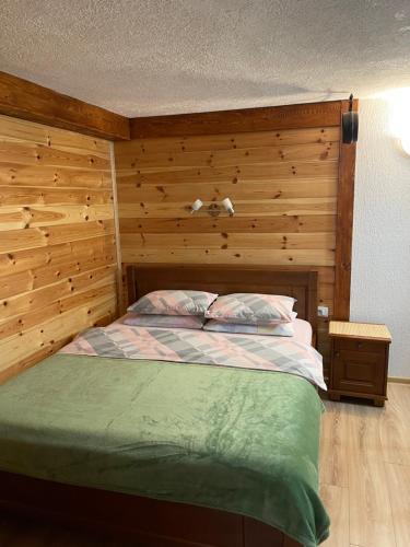 een slaapkamer met een bed met een houten muur bij Zabljak studio apartment 2 in Žabljak