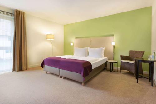 a hotel room with a bed and a table and chairs at Ramada by Wyndham München Airport in Oberding