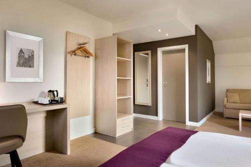 a bedroom with a bed and a desk and a couch at Ramada by Wyndham München Airport in Oberding