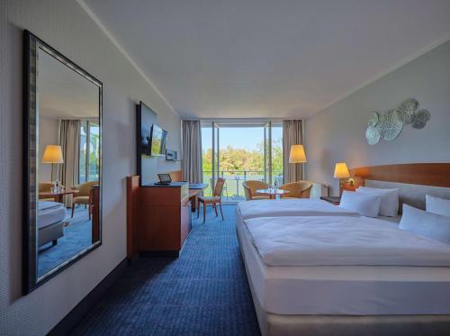 ビンツにあるDorint Seehotel Binz-Thermeのベッド2台と鏡が備わるホテルルームです。