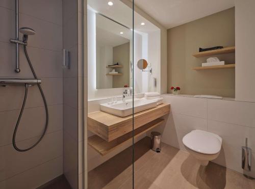 a bathroom with a shower and a sink and a toilet at Dorint Seehotel Binz-Therme in Binz