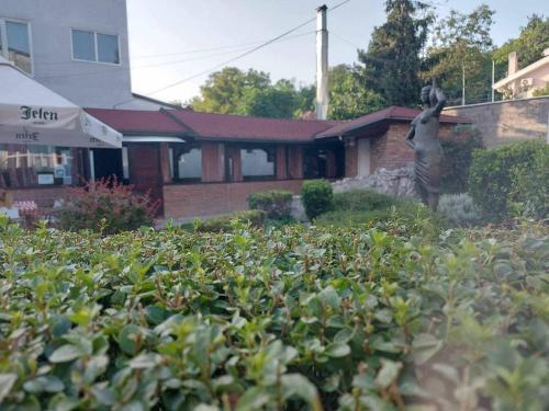 a garden with a statue in front of a house at Hotel Slodes in Belgrade