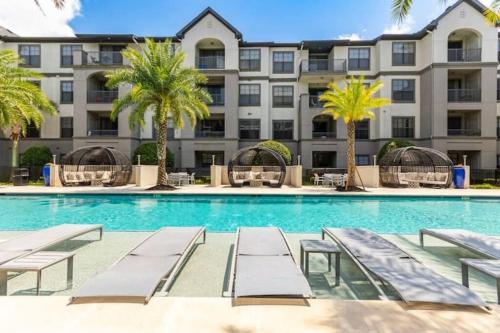 a swimming pool with chaise lounge chairs and a large building at NRG Stadium, the Medical Center Bright and Cozy Unit in Houston