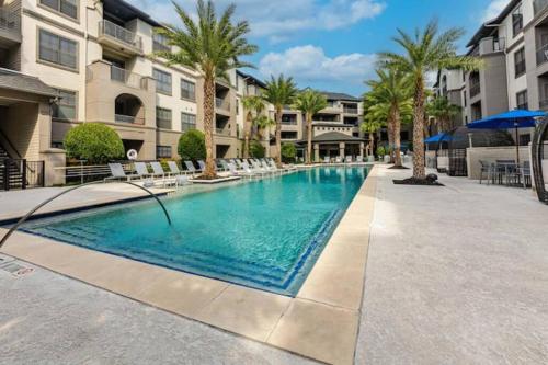 a swimming pool at a resort with chairs and palm trees at NRG Stadium, the Medical Center Bright and Cozy Unit in Houston