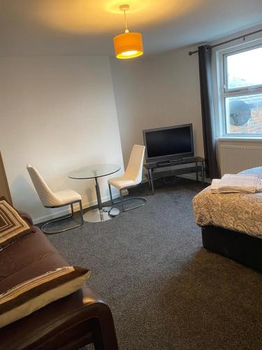 a room with a tv and a table and chairs at 2 Bedroom Flat with free parking in Manchester in Manchester