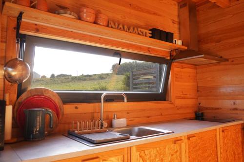 eine Küche mit einem Waschbecken und einem Fenster in einer Hütte in der Unterkunft Bungalow Blue - Cabana de Madeira in Nazaré