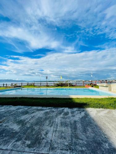 a swimming pool with the beach in the background at Nila's Staycation House in Dauis