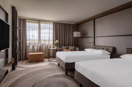 ジンデルフィンゲンにあるシュトゥットガルト マリオット ホテル ジンデルフィンゲンのベッド2台とテレビが備わるホテルルームです。