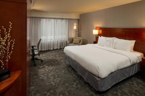 a hotel room with a large bed and a chair at Courtyard by Marriott Lafayette in Lafayette