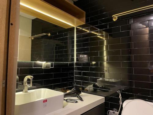 ein Badezimmer mit einem Waschbecken und einer schwarz gefliesten Wand in der Unterkunft 1BR with Balcony @ SMDC North Edsa Grass Residence Quezon City w/ Netflix & Disney + in Manila