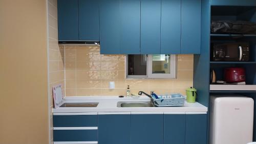 - une cuisine avec des placards bleus et un évier dans l'établissement White House, à Namhae