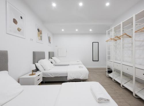 a white bedroom with two beds and white cabinets at No Limit Barcelona Central in Barcelona