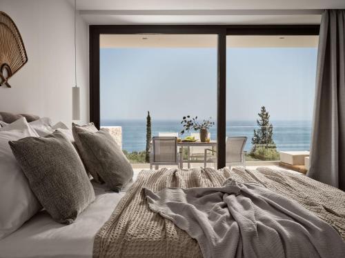 a bedroom with a bed with a view of the ocean at The Sall Suites - Complex B in Agios Nikolaos