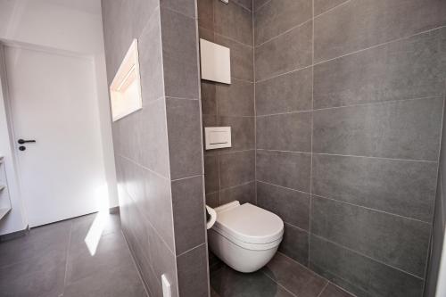 a bathroom with a toilet and a tiled wall at Mono Design Apartments in Stuttgart