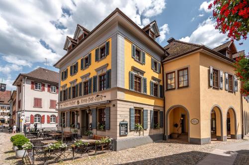 um edifício amarelo numa rua com mesas e cadeiras em stuub staufen em Staufen