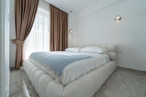 um quarto branco com uma grande cama branca em frente a uma janela em Altido Luxury Apartments em Budva