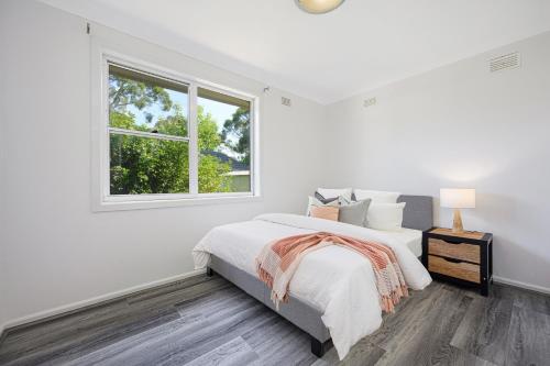 um quarto branco com uma cama e uma janela em Blacktown Renovated charming home & private yard em Blacktown
