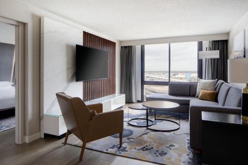 a living room with a couch and a room with a tv at Houston Marriott South at Hobby Airport in Houston