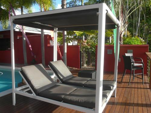 a gazebo with two lounge chairs next to a pool at Mai Tai Resort in Cassowary