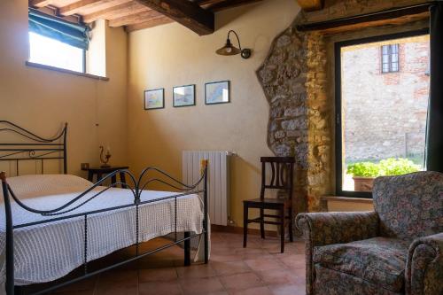 a bedroom with a bed and a chair and a window at Agriturismo Colli di Travale in Montieri