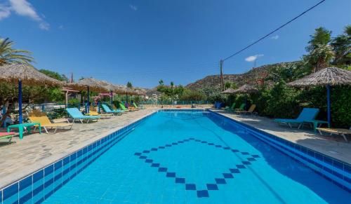 a swimming pool with chairs and umbrellas at a resort at Hotel Coral Matala in Matala