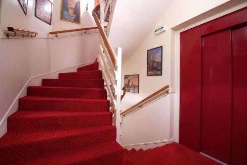 a stairway leading up to a room with red walls at Hotel de charme Les Mimosas in Pont-Aven