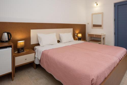 een slaapkamer met een groot bed en een roze deken bij Hotel Coral Matala in Matala