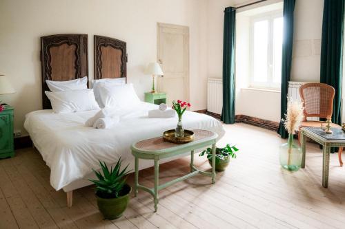 Un dormitorio con una gran cama blanca y una mesa en Chambres d'hôtes B&B - Château de Sienne proche Avignon Orange Piscine Rivière, en Chusclan