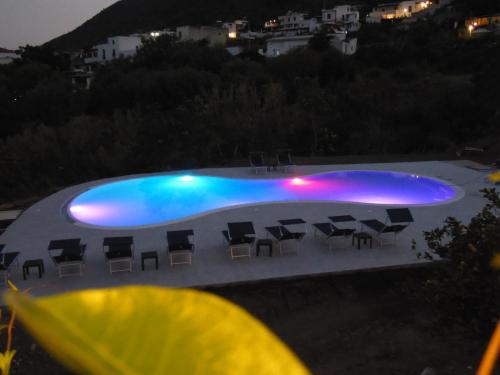 - une piscine avec des chaises et des lumières allumées la nuit dans l'établissement Hotel Da Franco Relax and Pool, à Santa Marina Salina