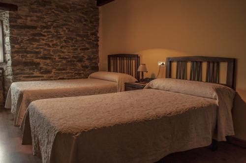 a bedroom with two beds and a brick wall at Apartamentos A Retoral in Coaña