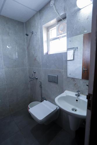 a bathroom with a sink and a toilet and a mirror at HOTEL SJ PRIDE in Bhubaneshwar