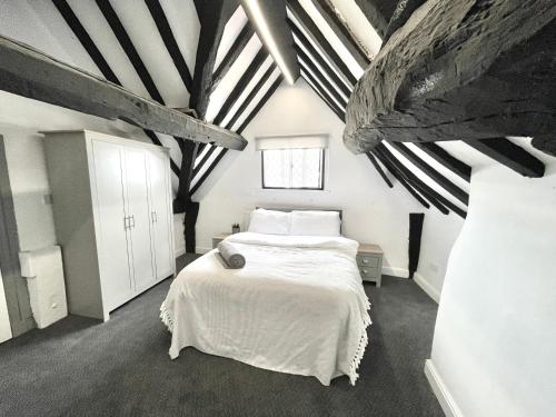 een slaapkamer met een wit bed in een kamer met balken bij 53 Church Street in Warrington