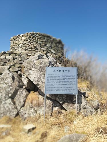 a sign on top of a hill with a stone wall at White House in Namhae