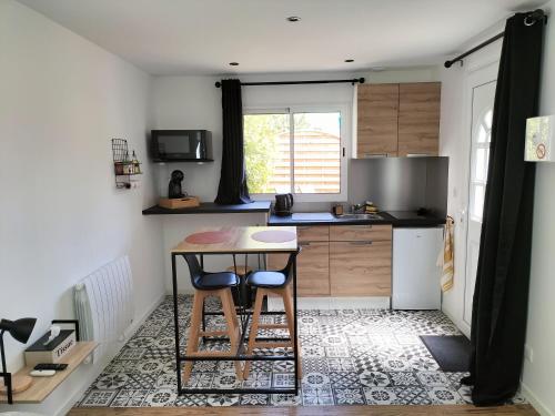 eine kleine Küche mit einem Tisch und 2 Hockern in der Unterkunft Studio - Au fond de la cour in Lacroix-Saint-Ouen