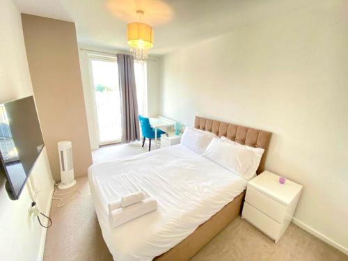 a bedroom with a large white bed with a desk at Canning Town 2 Bed Apartment in London