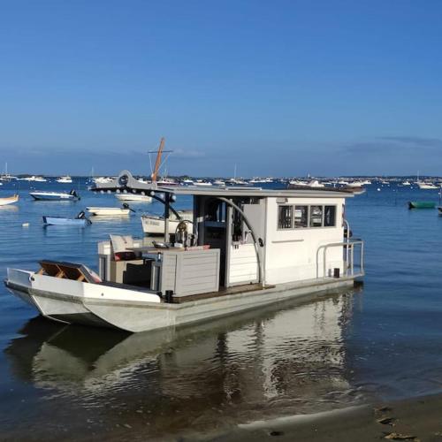 a white boat is docked in the water at Bateau nuit Insolite Astragale in Lège-Cap-Ferret