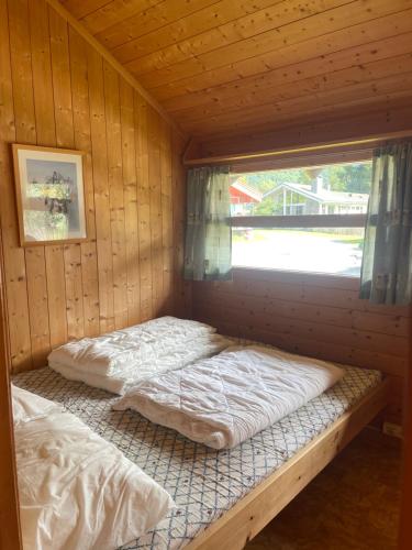 a room with two beds in a cabin with a window at Midttun Camping og Feriehytter in Vossestrand