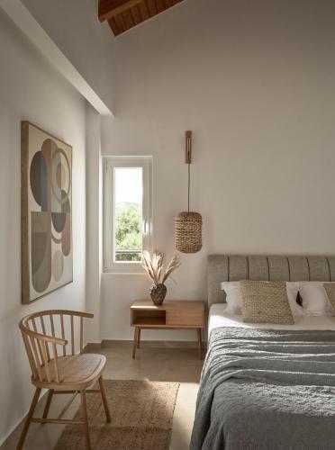 a bedroom with a bed and a chair and a window at La Maison Du Maire - Luxury Villa with Private Pool, by ZanteWize in Sarakinádhon