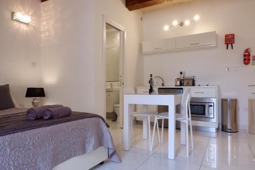 a bedroom with a bed and a table and a kitchen at SPQR Studios 2 Valletta in Valletta