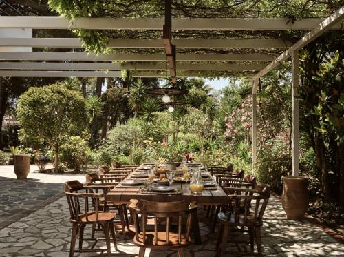 a long wooden table and chairs under a pergola at La Maison Du Maire - Luxury Villa with Private Pool, by ZanteWize in Sarakinádhon