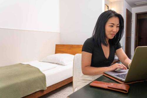 a woman sitting at a table using a laptop computer at magdas HOTEL Vienna City - First Social Business HOTEL in Austria in Vienna