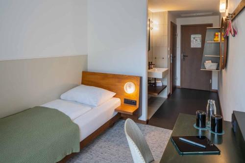 a bedroom with a bed and a desk and a table at magdas HOTEL Vienna City - First Social Business HOTEL in Austria in Vienna