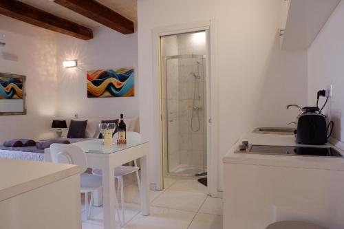 eine weiße Küche mit einem weißen Tisch und ein Badezimmer in der Unterkunft SPQR Studios 2 Valletta in Valletta