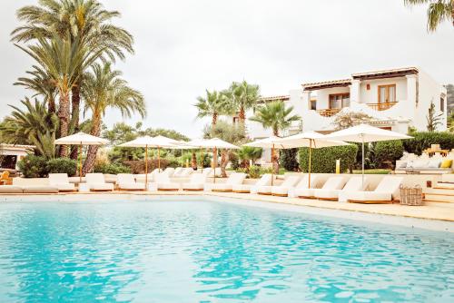 a swimming pool with lounge chairs and umbrellas at Petunia Ibiza, a Beaumier hotel in Cala Vadella