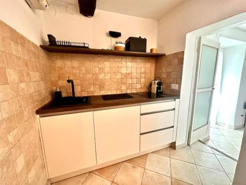 uma cozinha com armários brancos e uma parede de azulejos em Un petit coin proche de la mer em Menton