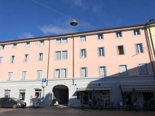 un gran edificio rosa con un coche aparcado delante de él en via Cappuccini 2b, en Gorizia