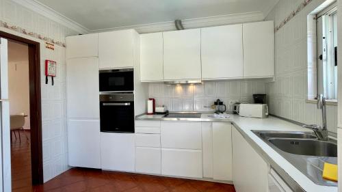 una cocina blanca con armarios blancos y fregadero en Poço by Check-in Portugal, en Albufeira