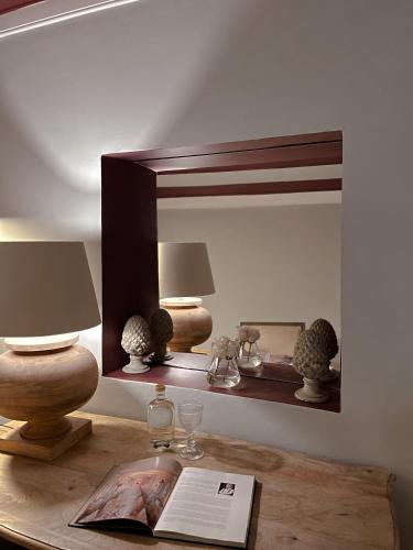 a mirror on a table with two lamps and a book at Palacio Ramalhete in Lisbon